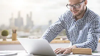 A man working on his laptop, view of a city in the background