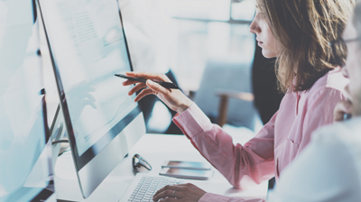 A businesswoman studying an item on her monitor