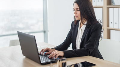 Woman in business attire working on a laptop in an office