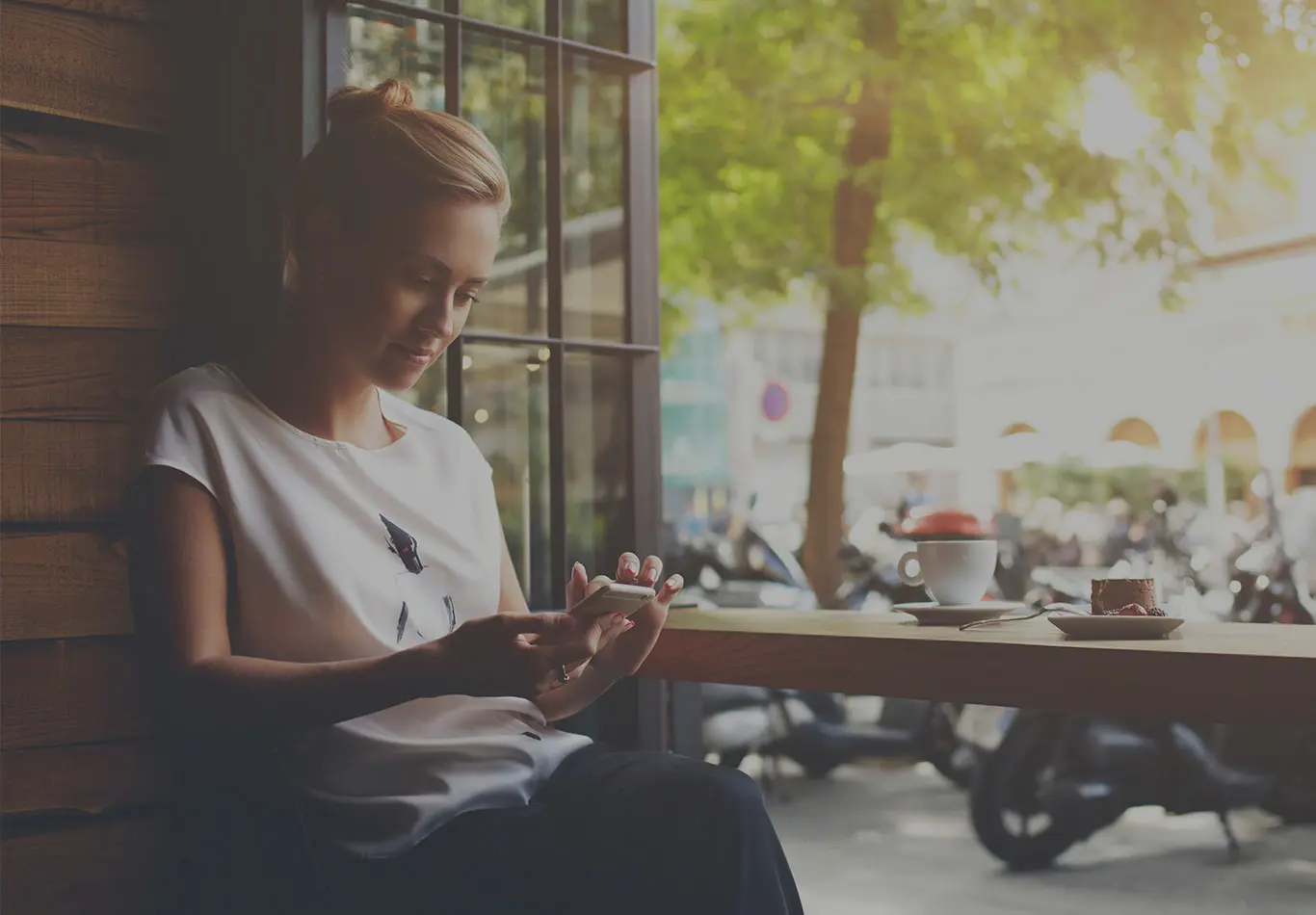 A woman with blonde hair is sitting looking at her phone. 