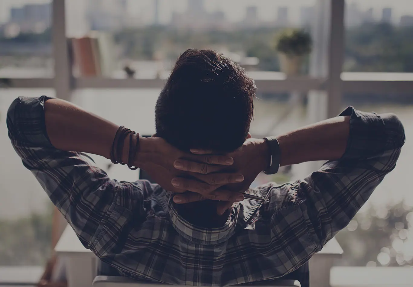 A man with his hands behind his back is looking out a windows