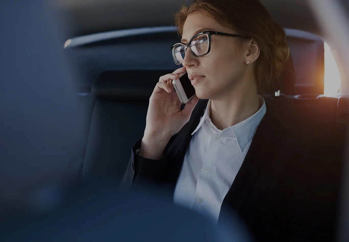 A woman is sitting in a car and talking on her phone 